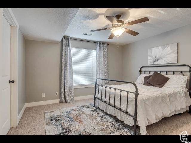 Carpeted bedroom with baseboards, a textured ceiling, and a ceiling fan