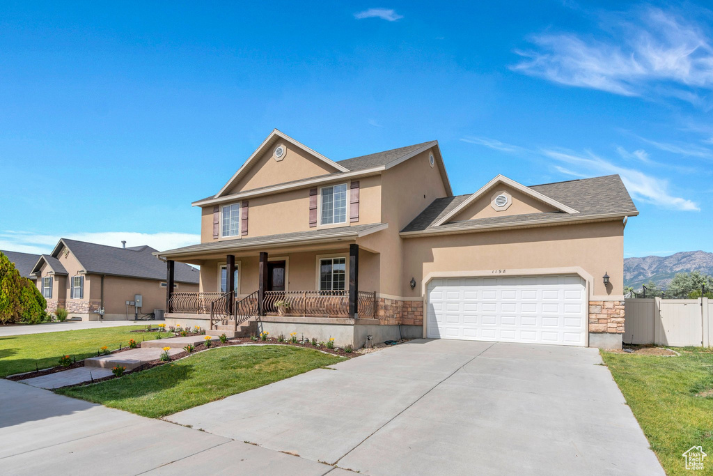 View of front of property with a porch, stucco siding, stone siding, concrete driveway, and a garage