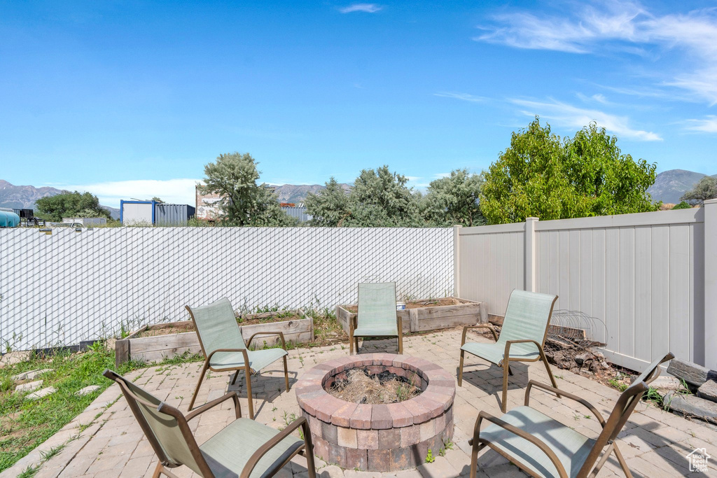 Fenced backyard featuring an outdoor fire pit, a patio, and a mountain view
