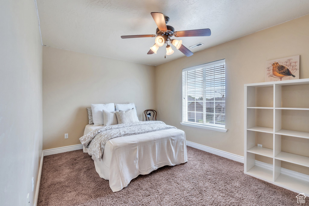 Carpeted bedroom featuring baseboards and a ceiling fan