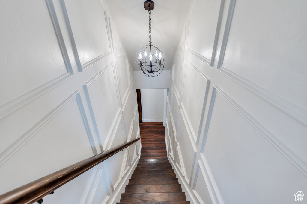 Stairway with a chandelier, wood-type flooring, and a decorative wall