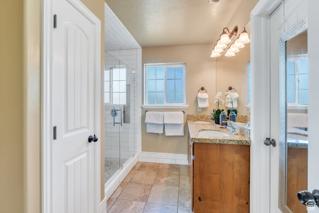 Bathroom with double vanity, a stall shower, and tile patterned flooring