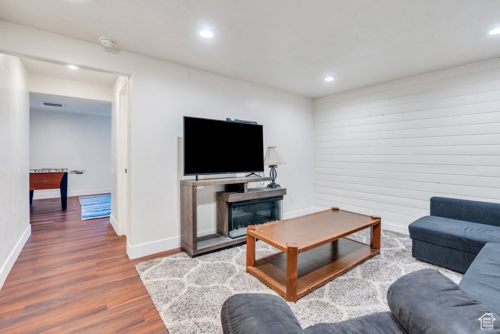 Living area featuring wood finished floors, recessed lighting, and a glass covered fireplace