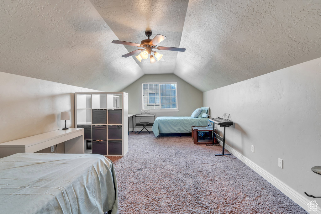 Bedroom featuring a textured ceiling, carpet, vaulted ceiling, and a ceiling fan