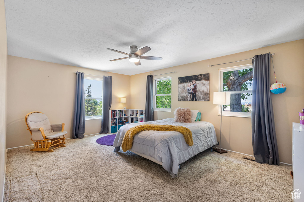 Carpeted bedroom with ceiling fan and a textured ceiling