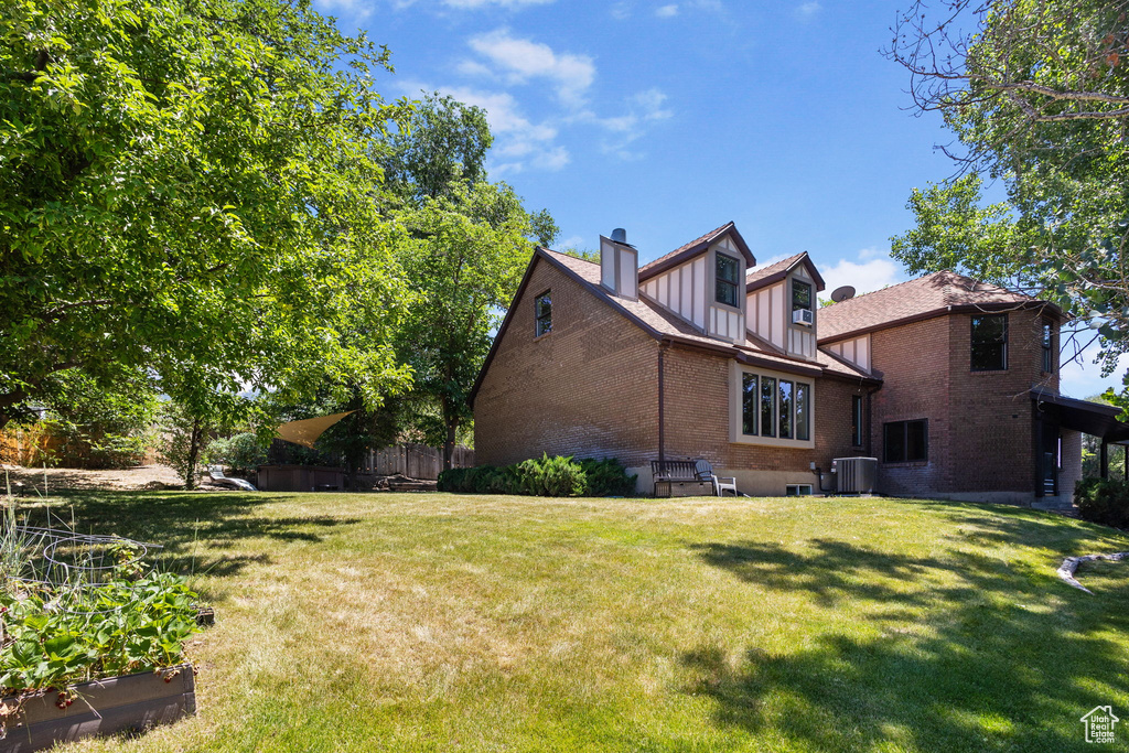 Rear view of house with brick siding, a yard, a chimney, and board and batten siding