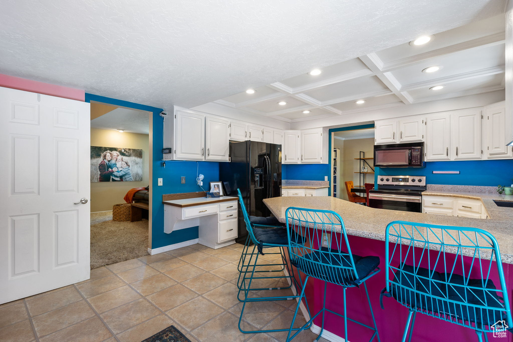 Kitchen with black appliances, recessed lighting, white cabinets, light countertops, and a peninsula