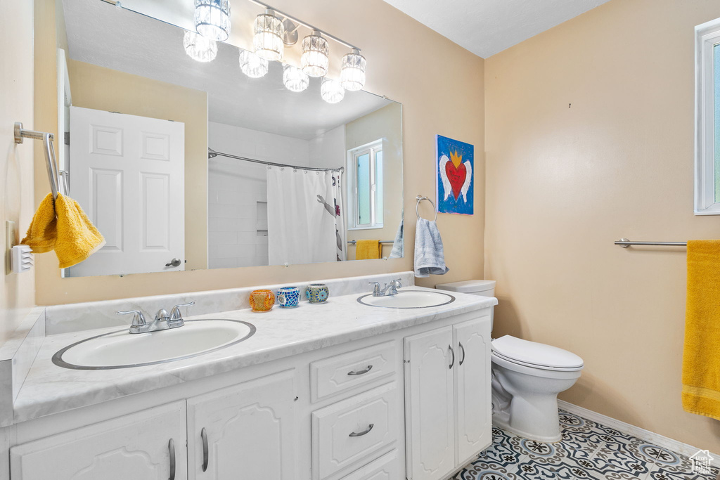 Full bathroom with double vanity, a shower with shower curtain, and tile patterned floors