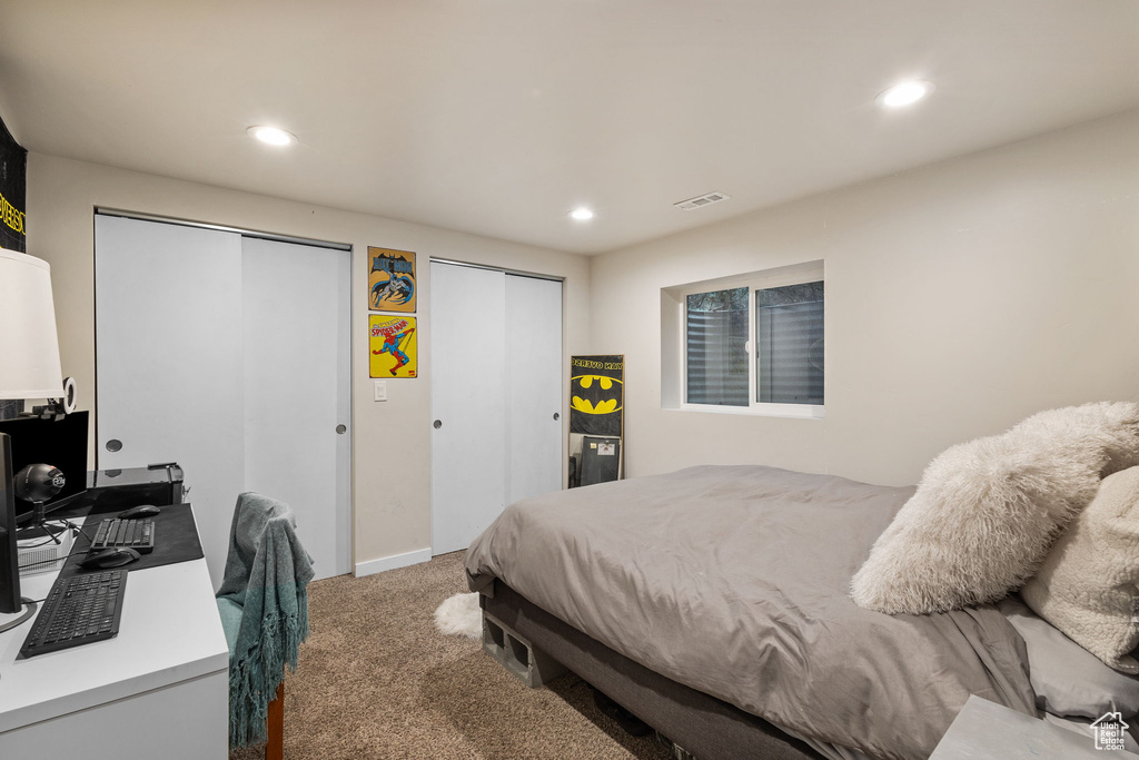 Carpeted bedroom with two closets, recessed lighting, and a desk