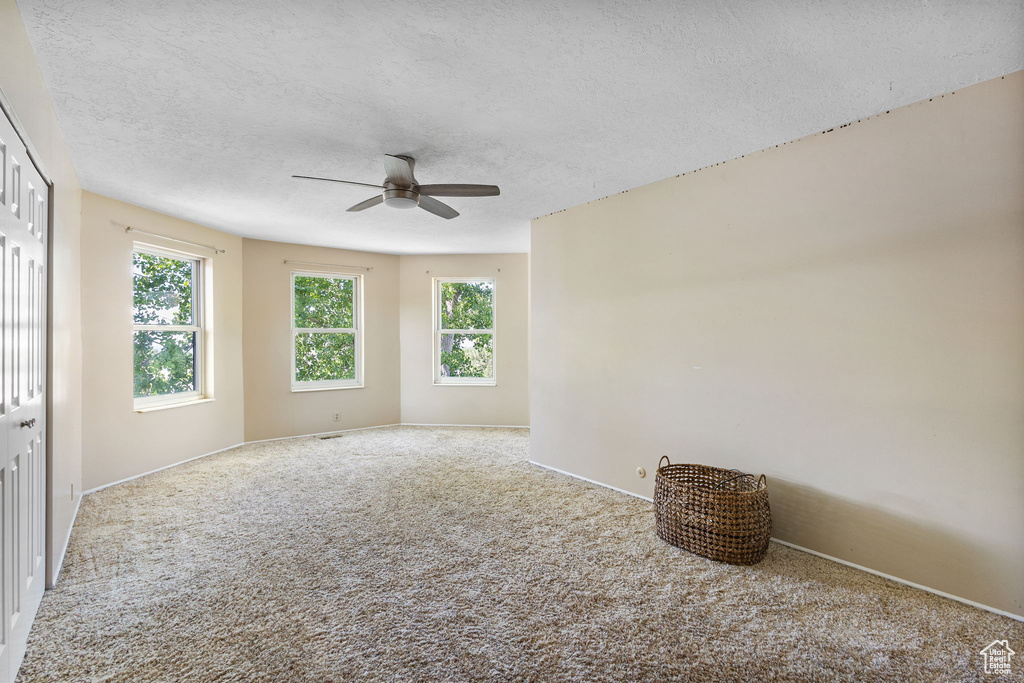 Carpeted empty room featuring a ceiling fan and a textured ceiling
