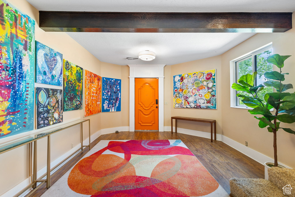 Entrance foyer with wood finished floors and beam ceiling