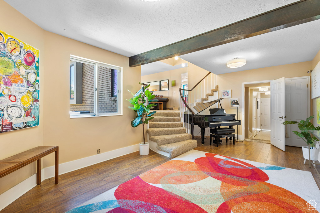 Foyer entrance featuring stairway, hardwood / wood-style floors, beam ceiling, and a textured ceiling