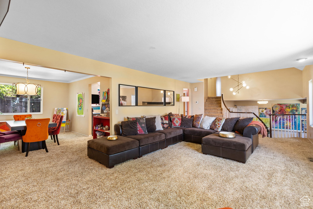 Carpeted living room with a chandelier, stairs, and crown molding