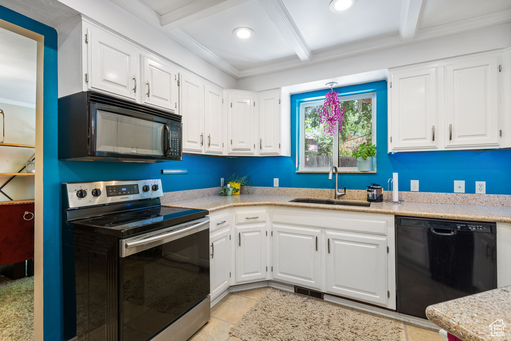 Kitchen featuring black appliances, beamed ceiling, light countertops, white cabinetry, and crown molding