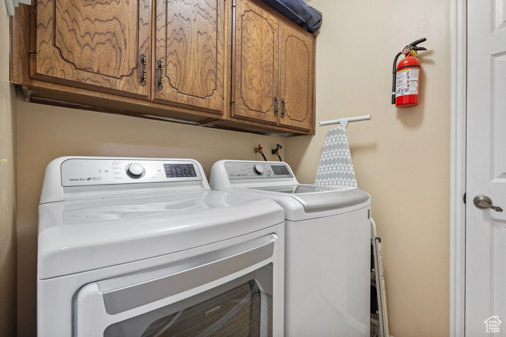 Washroom featuring independent washer and dryer and cabinet space