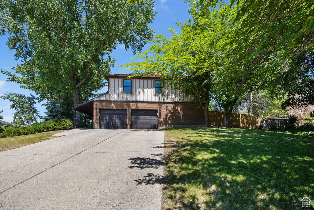 View of front facade with driveway, board and batten siding, brick siding, and an attached garage