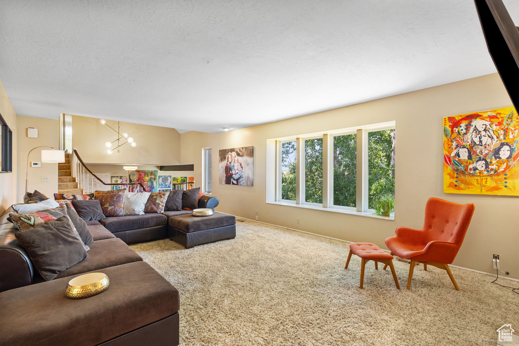 Carpeted living room featuring stairway, a chandelier, and a textured ceiling