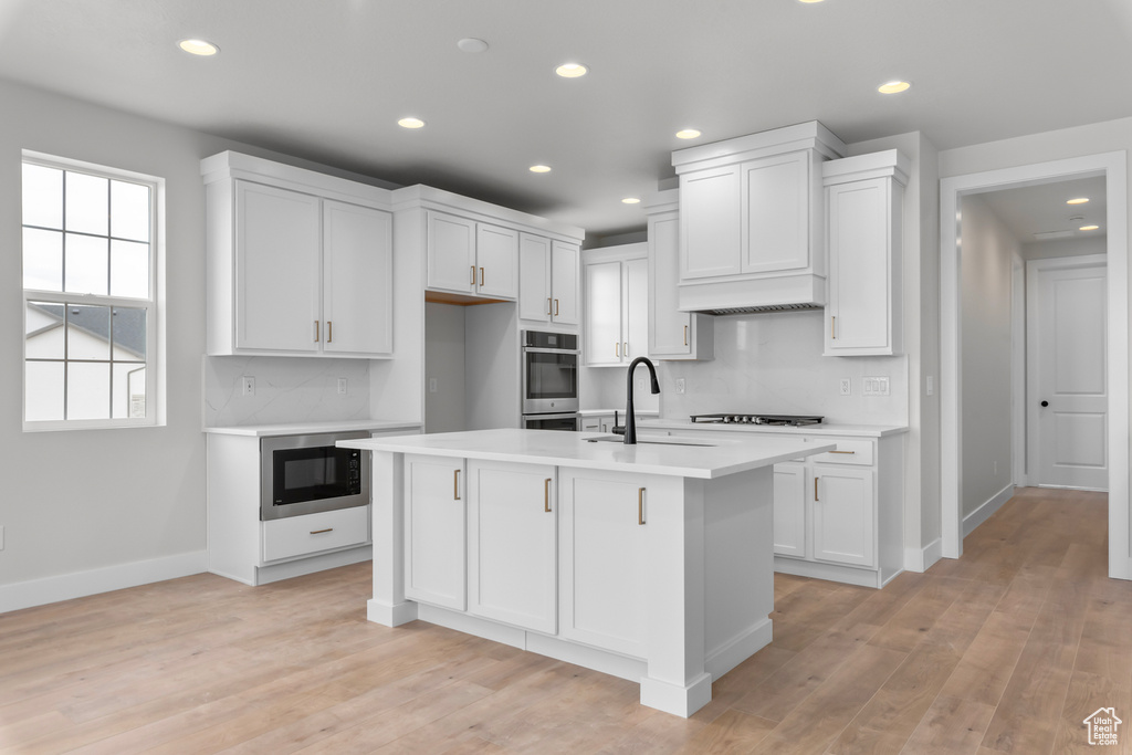 Kitchen with built in microwave, light countertops, recessed lighting, gas stovetop, and white cabinets