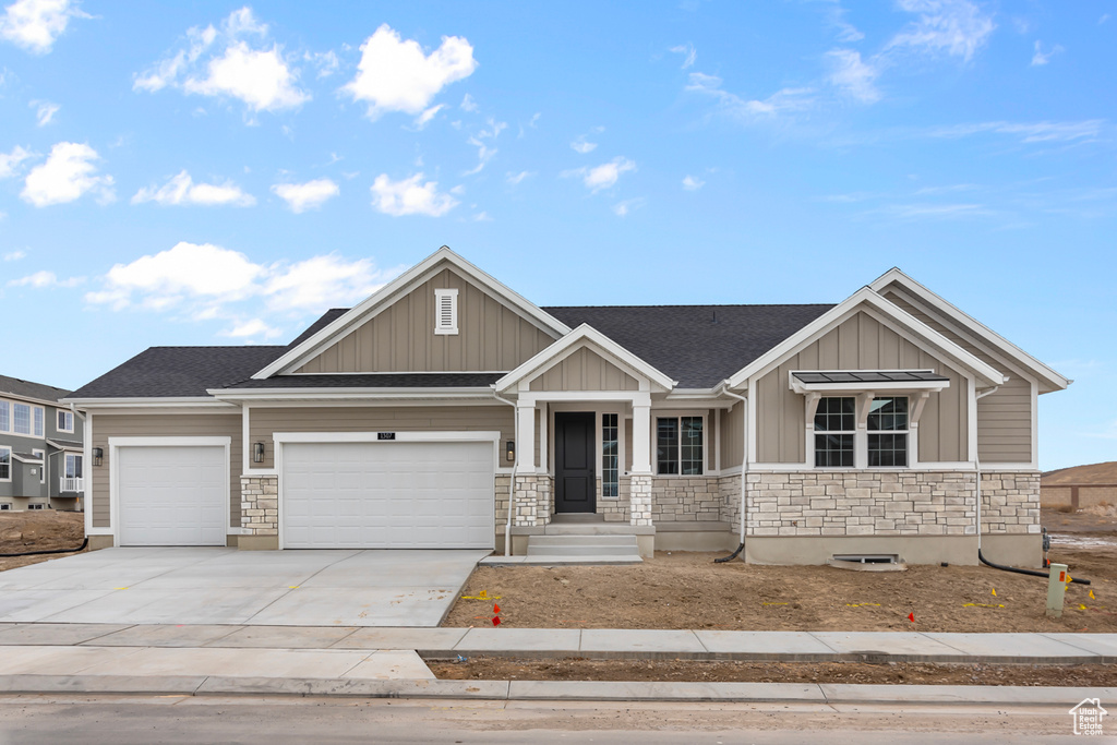Craftsman inspired home with stone siding, driveway, a garage, board and batten siding, and a shingled roof