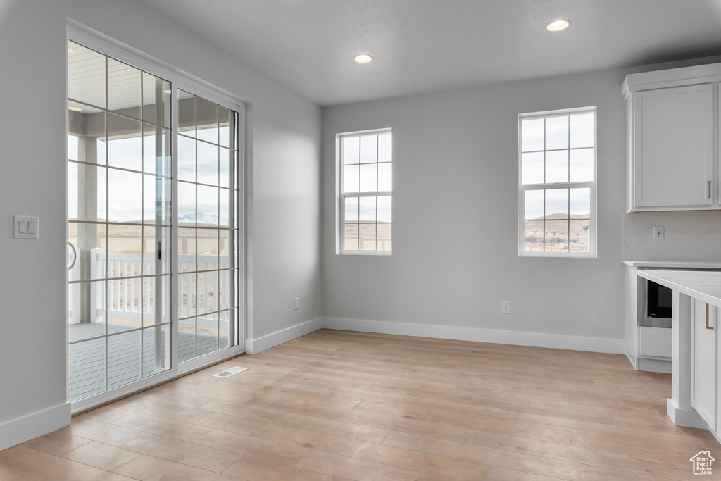 Unfurnished dining area featuring light wood-type flooring and recessed lighting