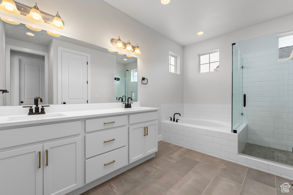 Bathroom featuring a stall shower, double vanity, a garden tub, and recessed lighting