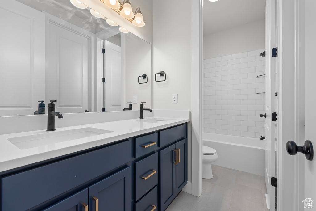 Full bathroom with double vanity, tile patterned flooring, and shower / bath combination