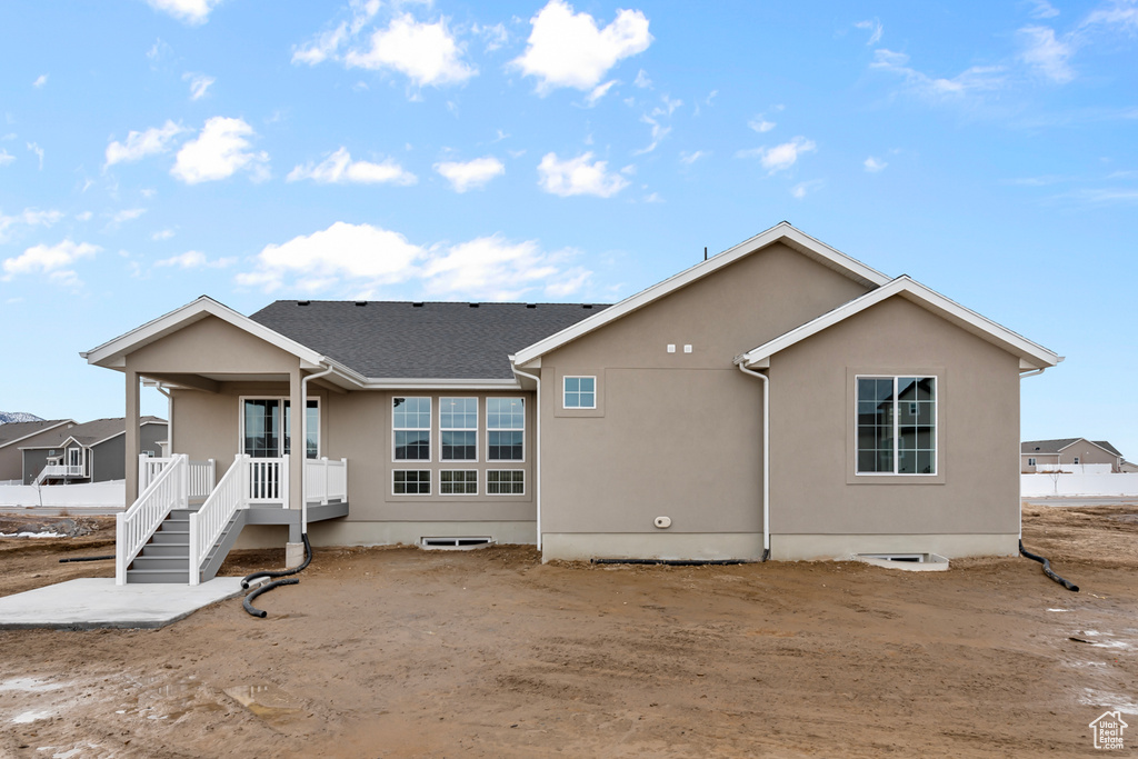 Back of house featuring stucco siding and covered porch