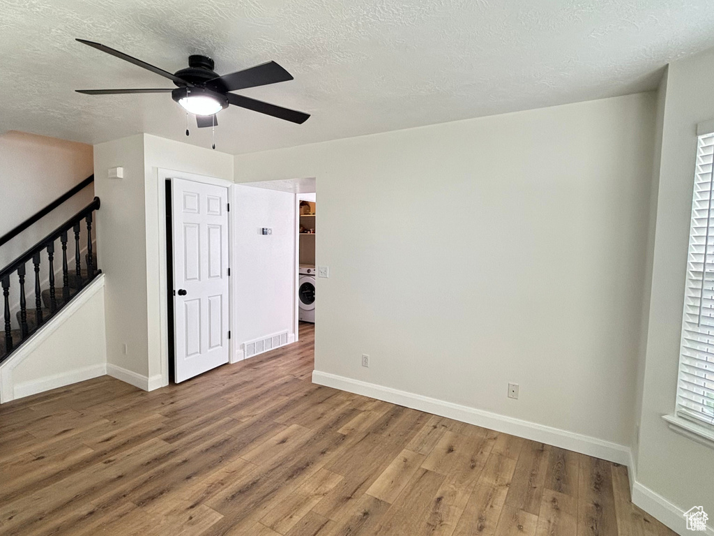 Unfurnished room with ceiling fan, hardwood / wood-style floors, a textured ceiling, and washer / dryer