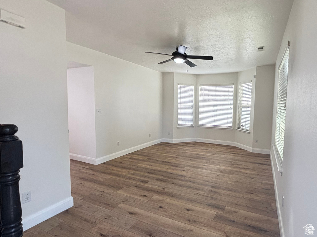 Unfurnished room featuring a textured ceiling, dark hardwood / wood-style floors, and ceiling fan