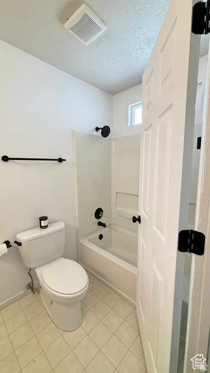 Bathroom with tile patterned floors, tub / shower combination, toilet, and a textured ceiling