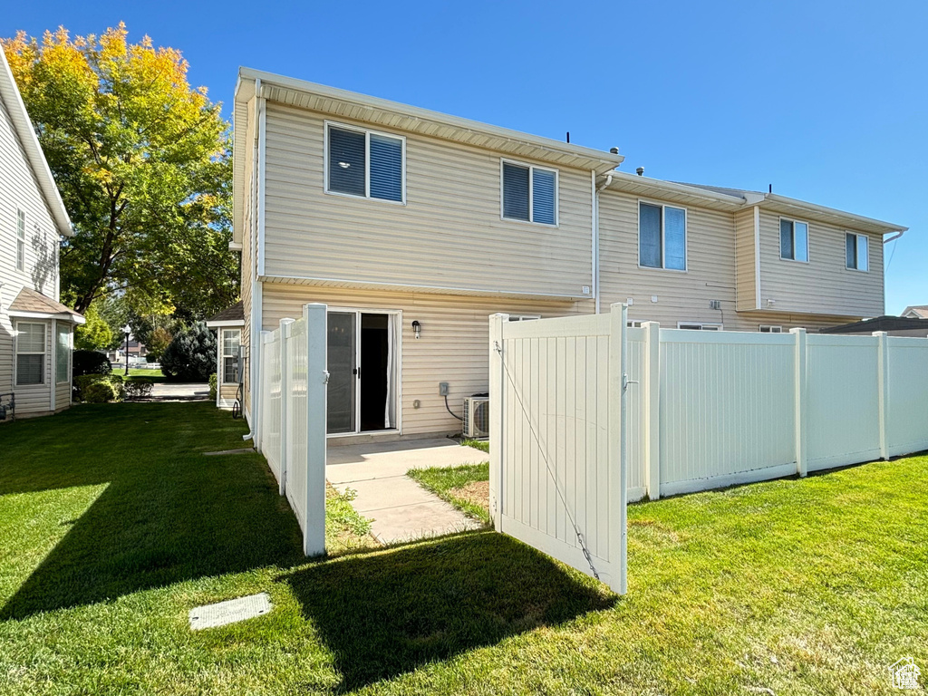 Rear view of house featuring a patio, a yard, and central AC
