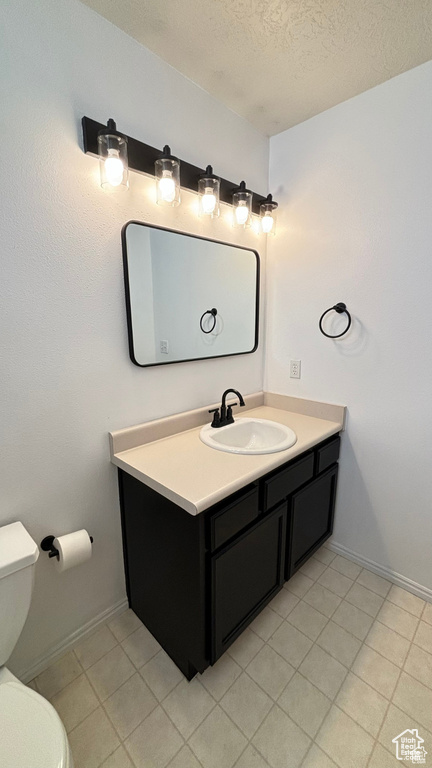 Bathroom featuring tile patterned floors, vanity, a textured ceiling, and toilet