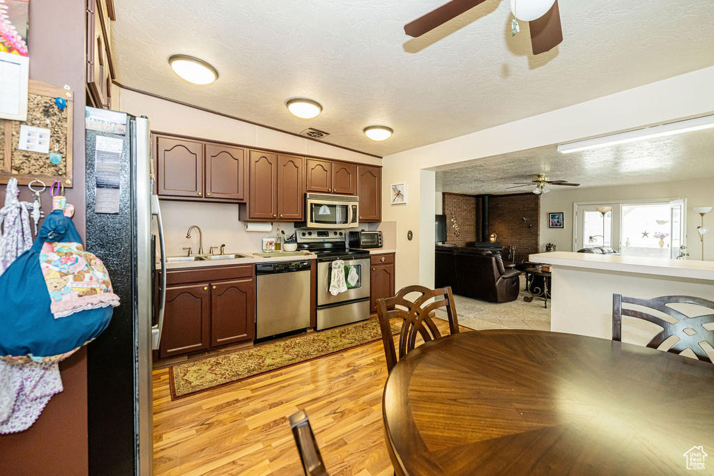 Kitchen with appliances with stainless steel finishes, ceiling fan, a textured ceiling, open floor plan, and light countertops
