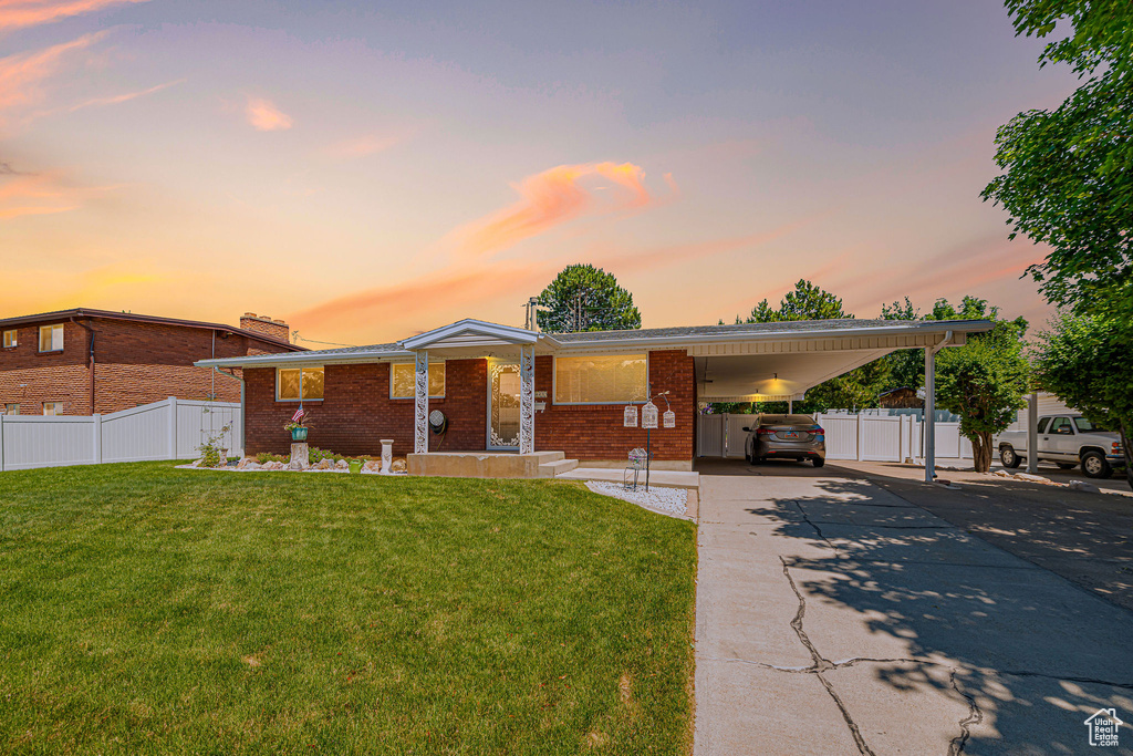 View of front of home with brick siding, concrete driveway, an attached carport, and a chimney