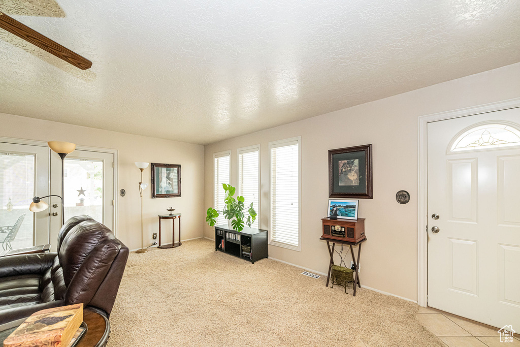 Entryway featuring a textured ceiling, light carpet, and a ceiling fan