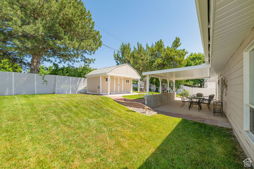 Fenced backyard featuring a patio and an outdoor structure
