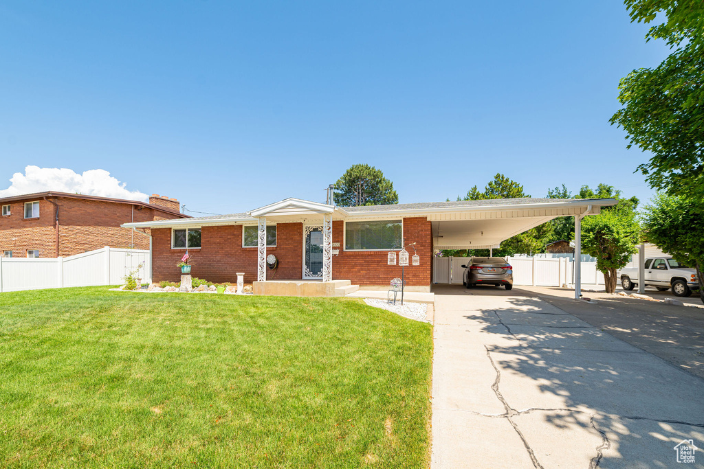 View of front of property featuring brick siding, concrete driveway, and an attached carport