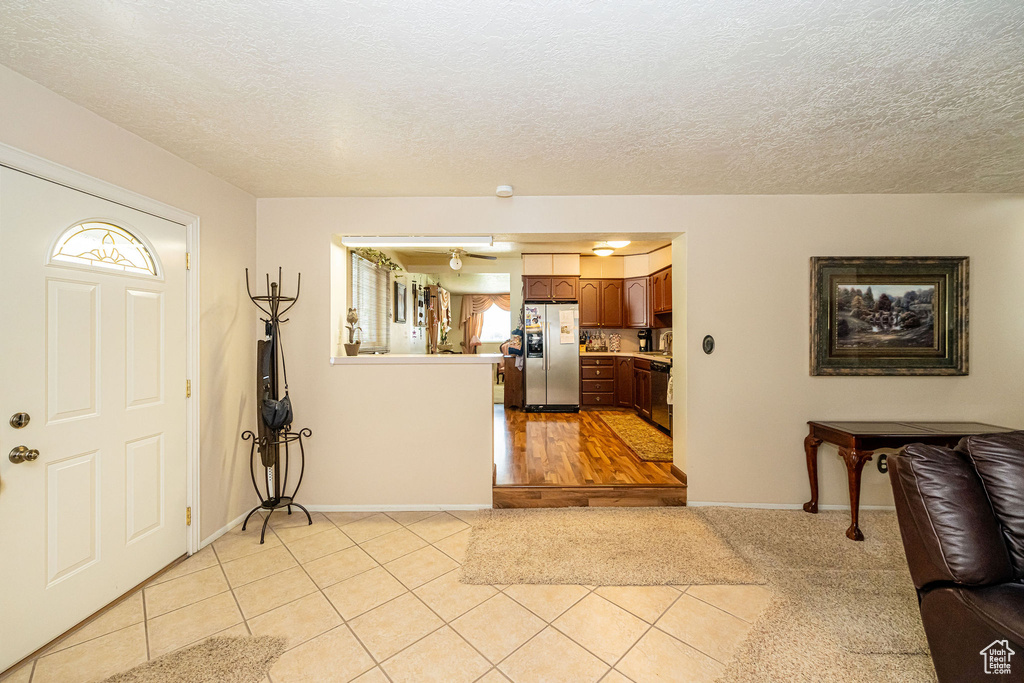 Foyer entrance with light tile patterned flooring and a textured ceiling