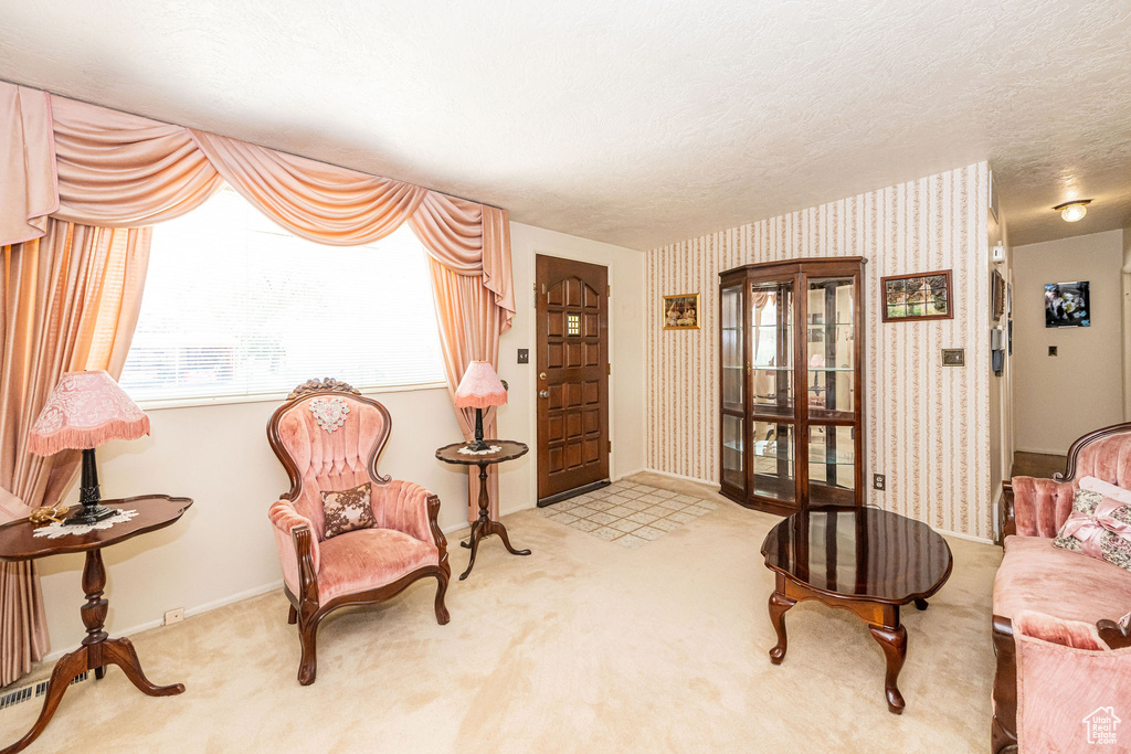 Sitting room with wallpapered walls, carpet floors, and a textured ceiling