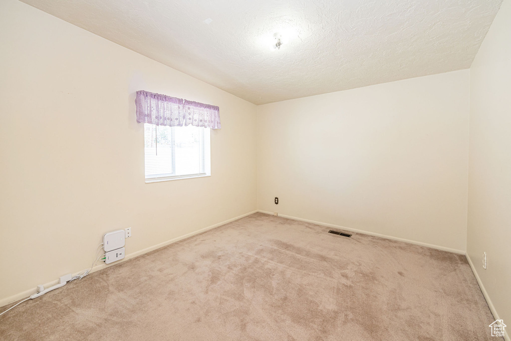 Carpeted empty room featuring baseboards and a textured ceiling