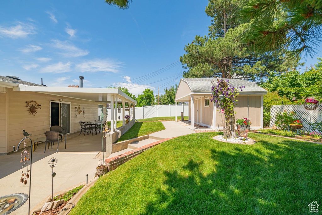 Fenced backyard with an outdoor structure and a patio area