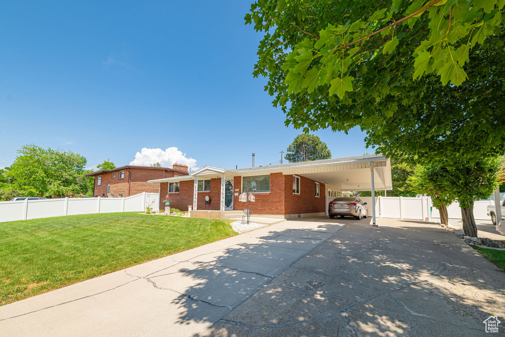 Back of house featuring brick siding, concrete driveway, an attached carport, and a chimney