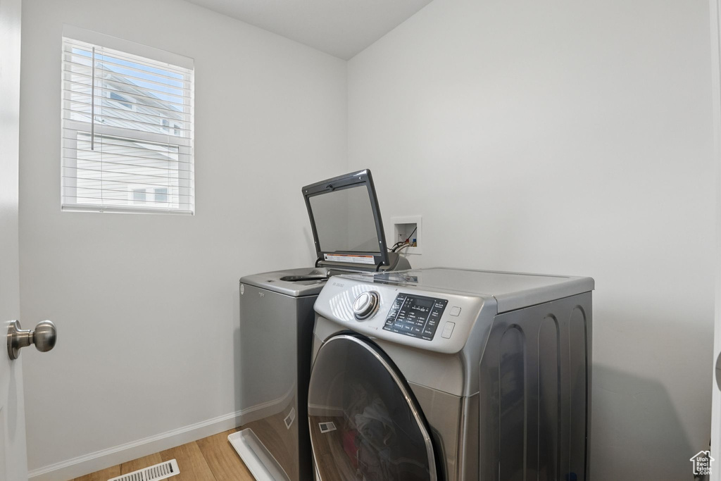 Laundry area with washing machine and clothes dryer and light wood-type flooring