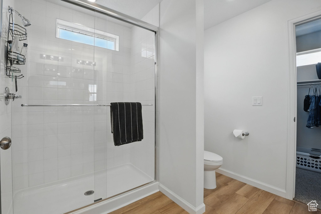Full bath with wood finished floors, a stall shower, and a spacious closet