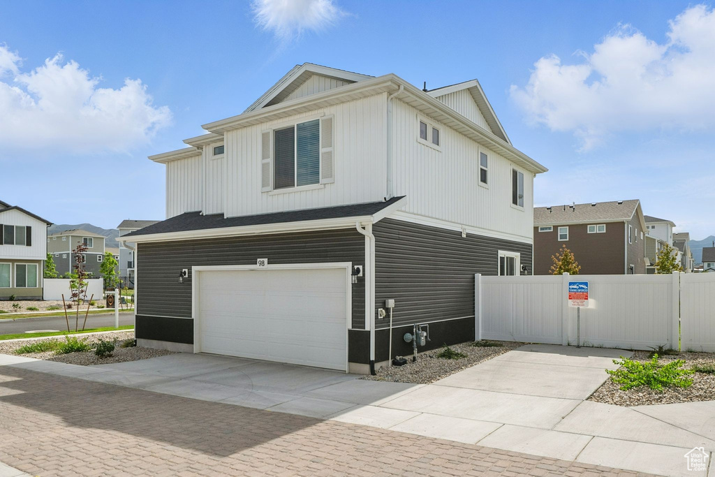 View of side of home with an attached garage, concrete driveway, and a residential view