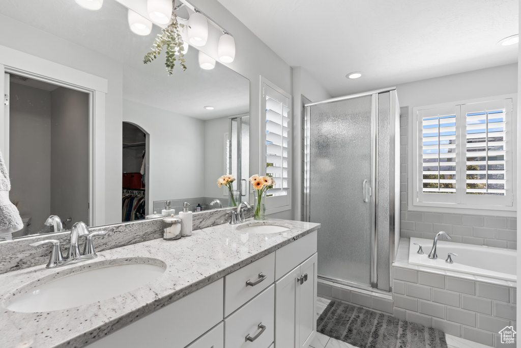 Bathroom featuring a stall shower, double vanity, a spacious closet, a bath, and recessed lighting