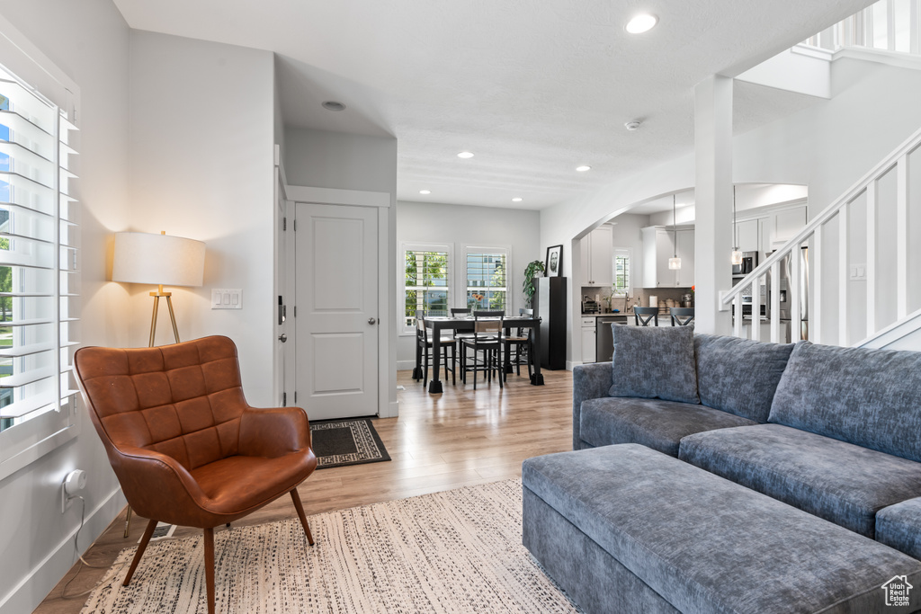 Living room featuring arched walkways, light wood-style floors, recessed lighting, and stairs