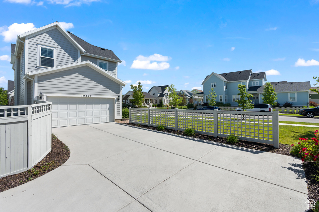View of property exterior with a residential view, a garage, and driveway