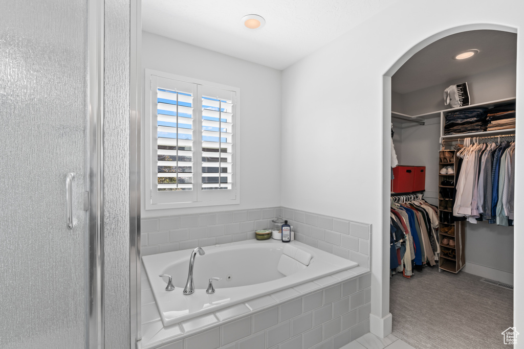 Bathroom featuring a jetted tub, a walk in closet, a shower stall, and recessed lighting