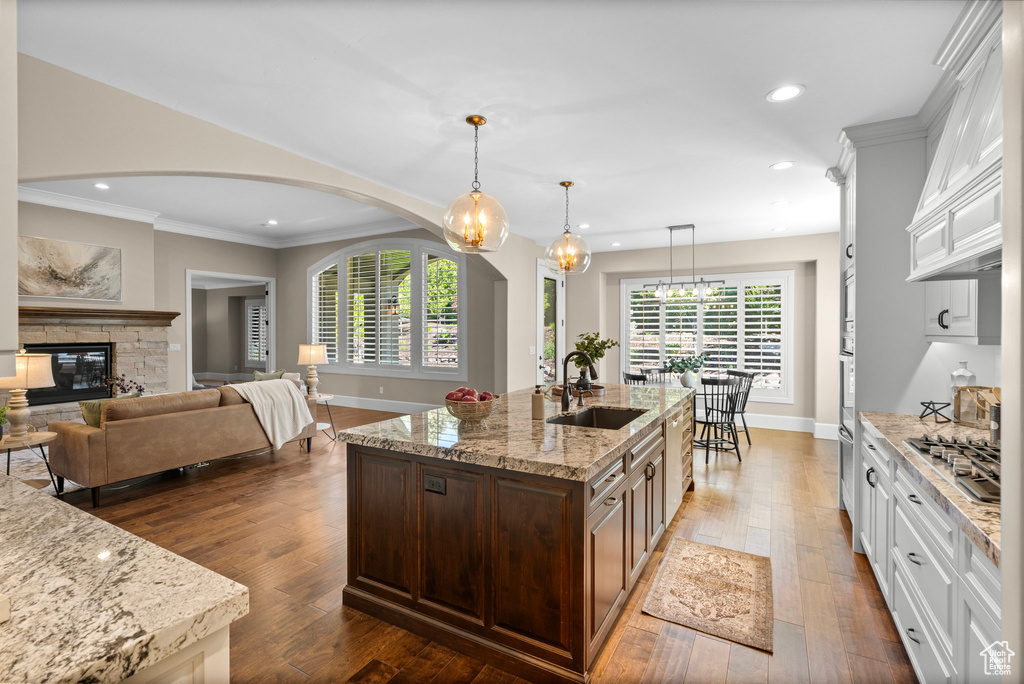 Kitchen with arched walkways, white cabinetry, ornamental molding, recessed lighting, and light stone counters